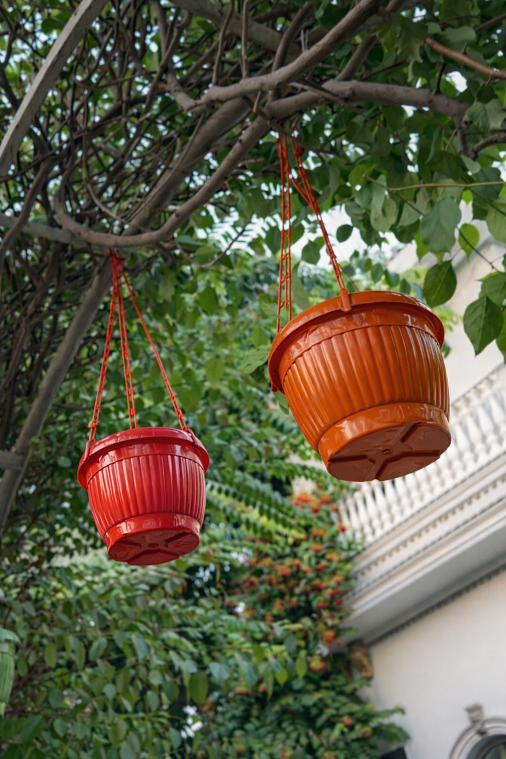 Two red hanging planters attached to tree branches with a blurred background